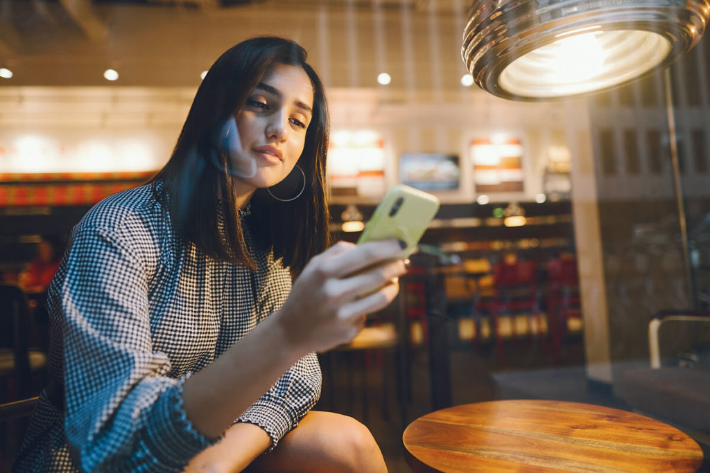 a woman from chicago using her phone while inside a nice bar