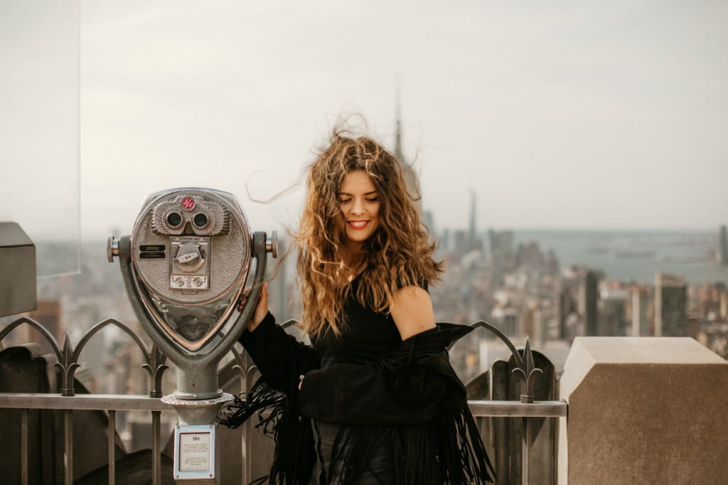 new york city girl using a telescope to check the view in the city