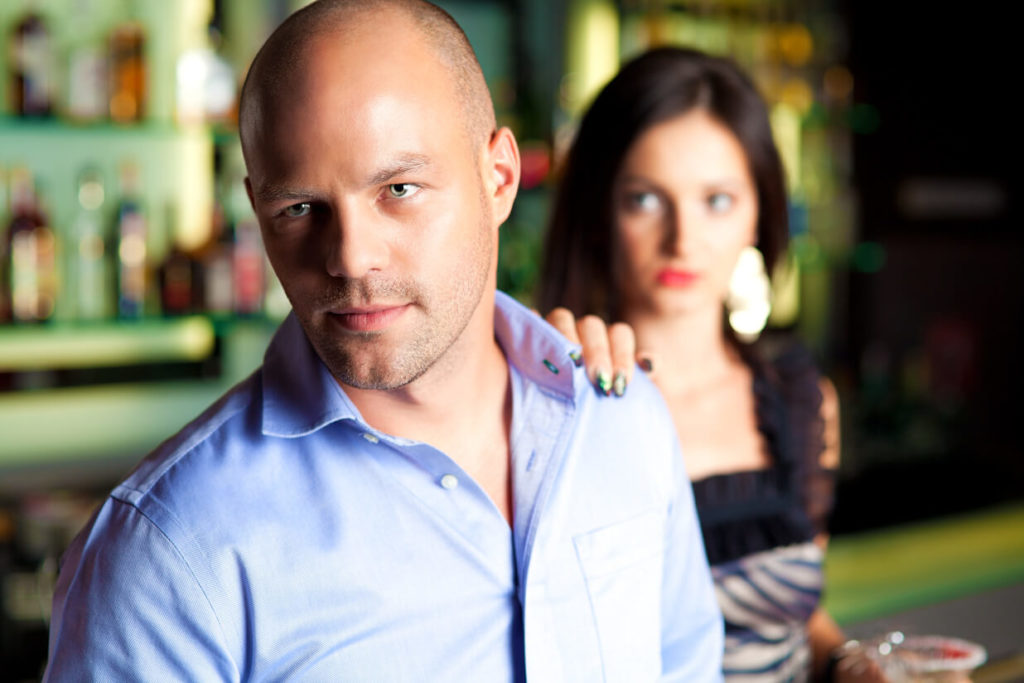 a woman from fort worth puts her hand on the shoulder of a man inside a bar