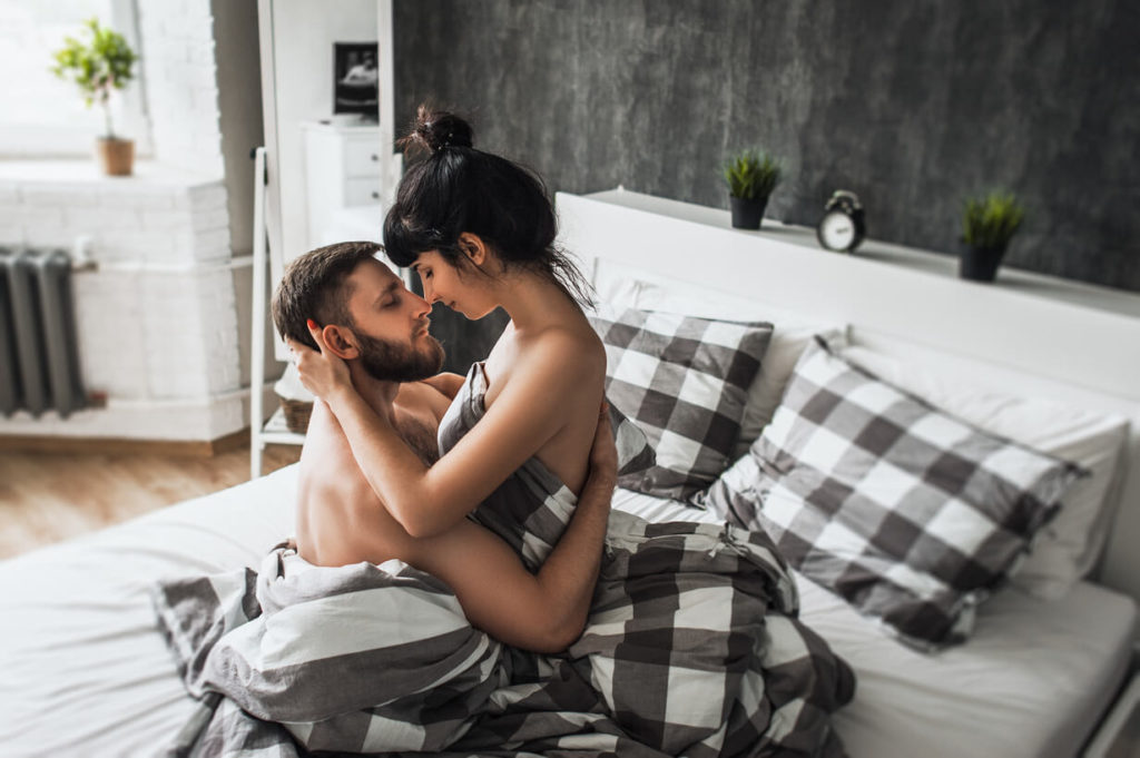 a young woman from el paso kisses a guy while they are on a bed