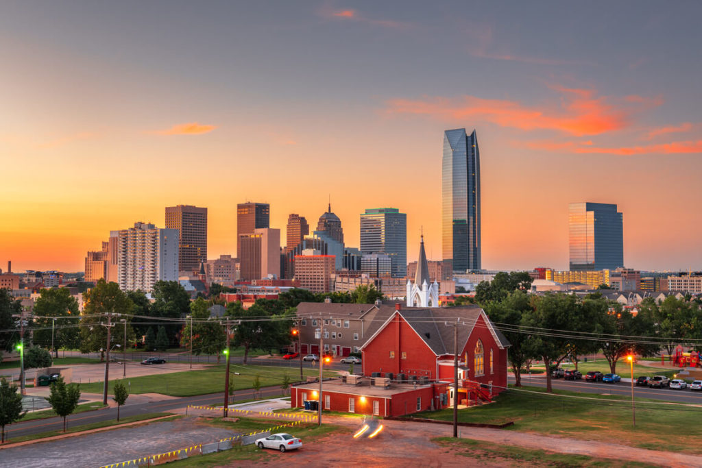 a view of oklahoma city with buildings and a red house in the background